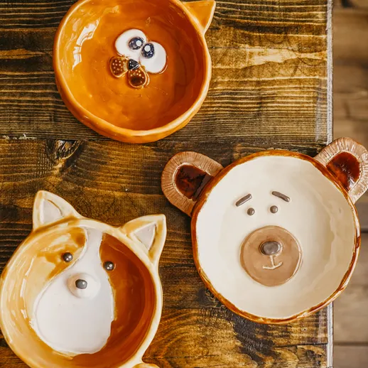 Керамические тарелки в виде животных на деревянном столе, интерьер кафе, уютная атмосфера
