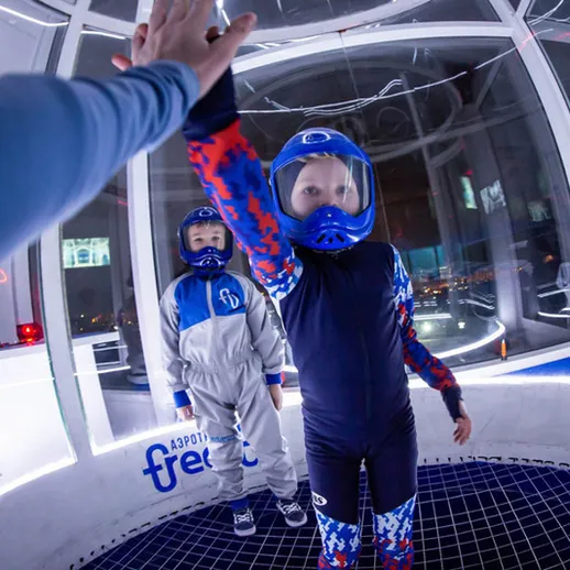 Дети в защитной экипировке на занятии по воздухоплаванию в закрытом тренажере