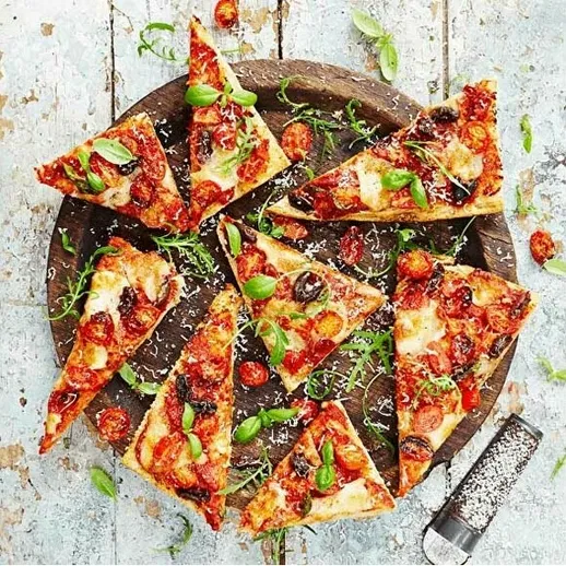 Вкусная пицца с томатами и базиликом, нарезанная на треугольники, подается на деревянной доске