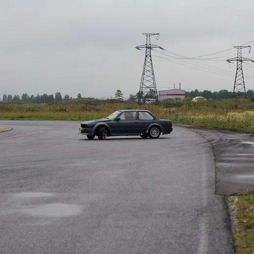 Дрифтующий спортивный автомобиль на пустой автодроме в дождливую погоду