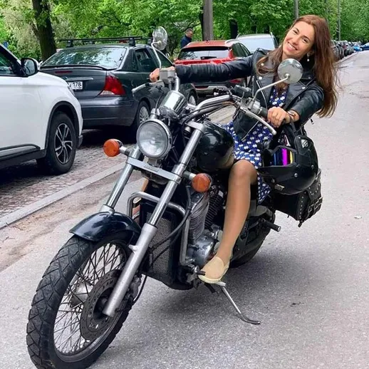 Женщина в кожаной куртке на мотоцикле катается по городскому маршруту в солнечный день