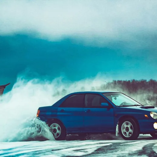 Синий автомобиль скользит по снежной дороге зимой в лесу, создавая облака снега и брызги воды