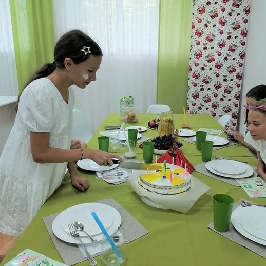 Праздничный стол с тортом и угощениями для детей в ярком интерьере на день рождения в уютном помещении