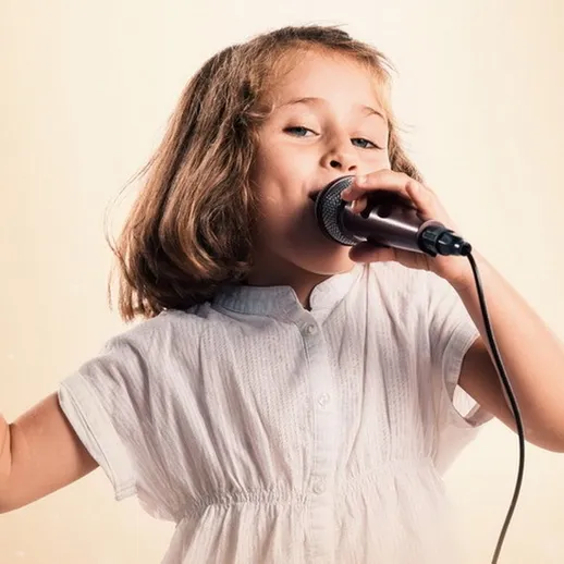 Девочка поет в микрофон на сцене, освещенной мягким светом, демонстрируя свои таланты на караоке-вечере