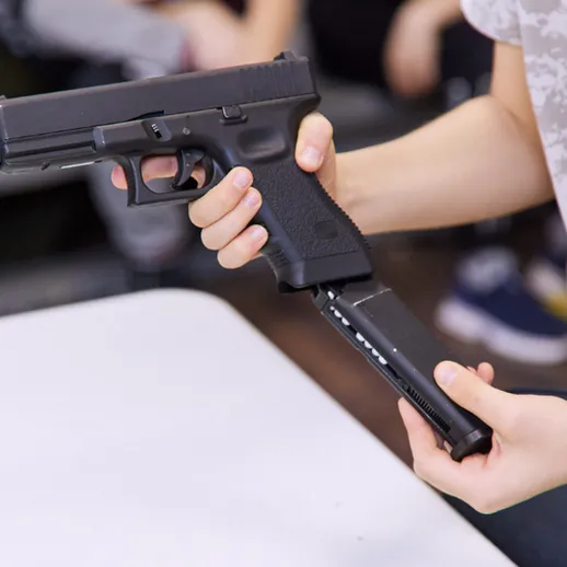 Молодой человек держит пистолет на учебном занятии по безопасности в классе