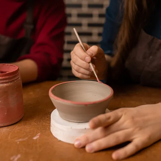 Изготовление керамической посуды в творческой мастерской, где участники рисуют на свежевыпеченной чаше