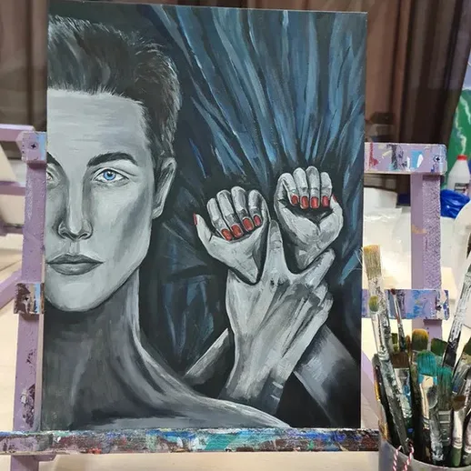 Молодой человек с выразительными глазами и красными ногтями на фоне темной ткани в художественной мастерской