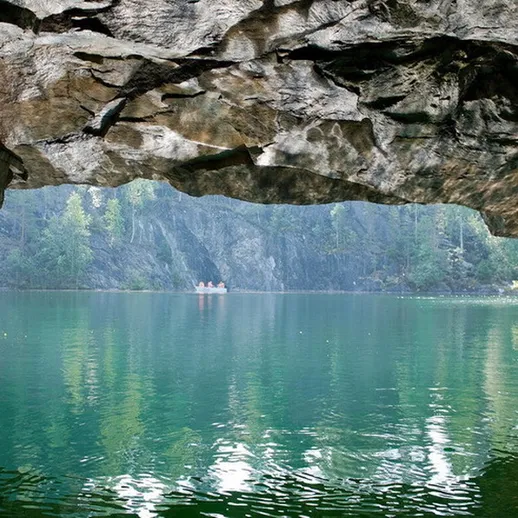 Узкие каменные арки, отражающие спокойный водоём, окружённый лесом в живописном карьере, солнечный день