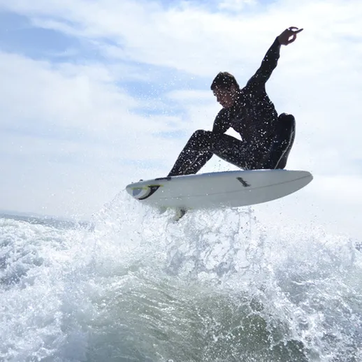 Серфингист прыгает на волне под облачным небом на пляже в летний день