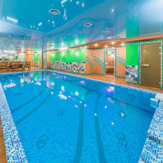Внутренний бассейн с голубой водой и зеленой отделкой в уютном помещении