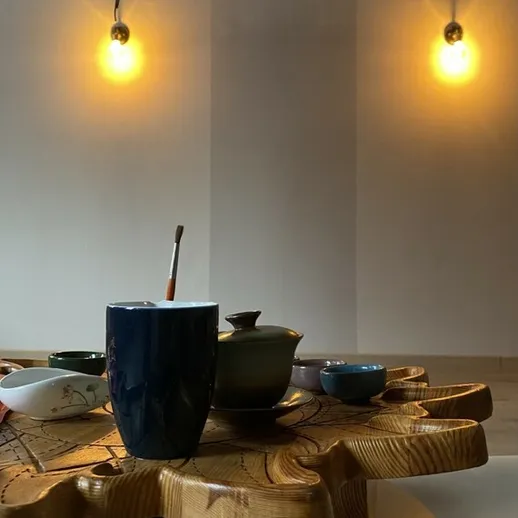 Красивая чаша и чайник на деревянном столе в уютном помещении с мягким светом