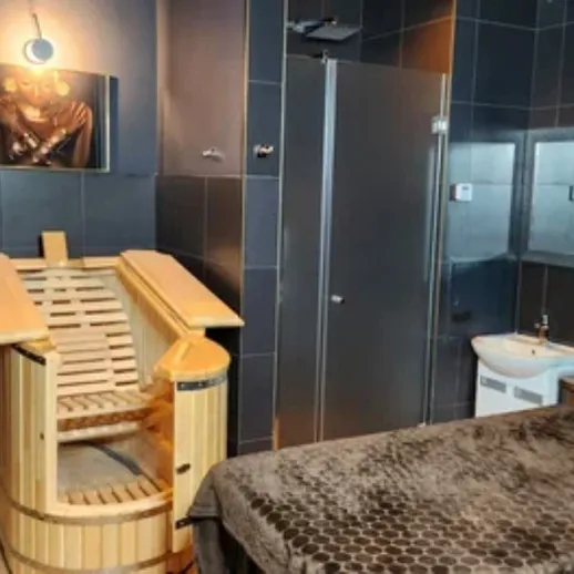 Уютная спа-комната с деревянной сауной, душем и массажной койкой в современном интерьере