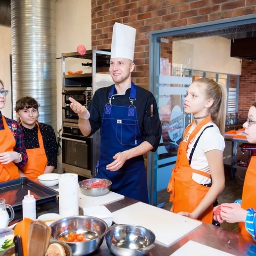 Дети учатся готовить под руководством шеф-повара на кулинарном мастер-классе в современном ресторане