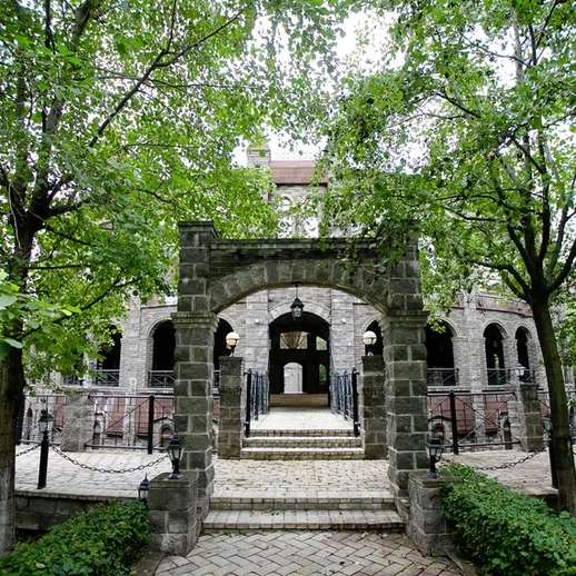 Уютный замок с каменной аркой, окруженный зелеными деревьями в солнечный день