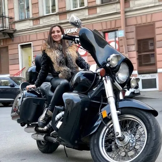 Девушка на черном мотоцикле на улице в городе, наслаждающаяся поездкой в зимний день