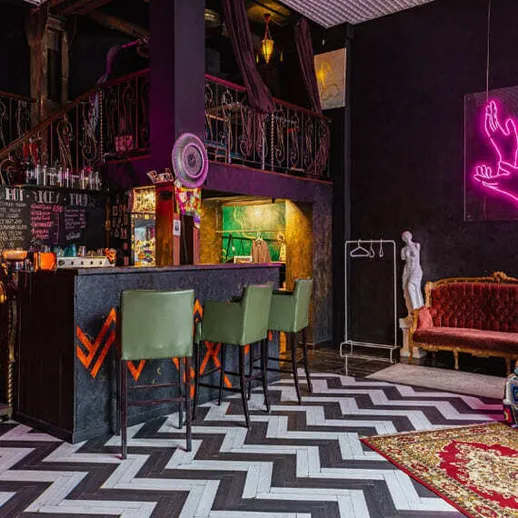 Уютный бар с неоновыми огнями и стильной мебелью в интерьере, украшенном яркими деталями и художественными элементами