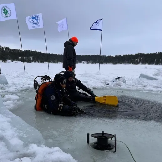 Подводные исследователи работают на ледяной поверхности озера во время зимней экспедиции