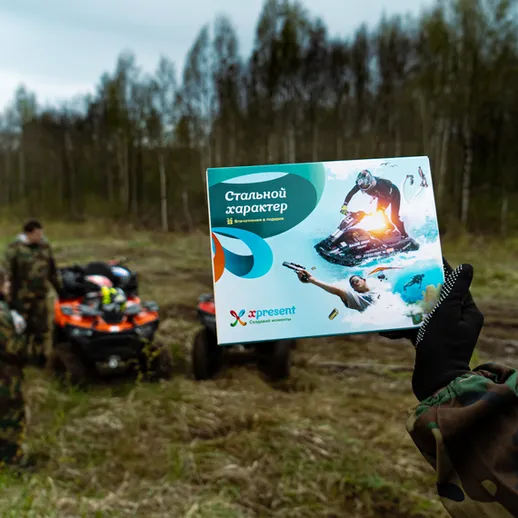 Участник мероприятия демонстрирует рекламную карточку с информацией о активном отдыхе на квадроциклах в лесу