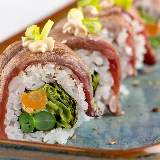 Суши с говядиной и овощами на синей тарелке в ресторане