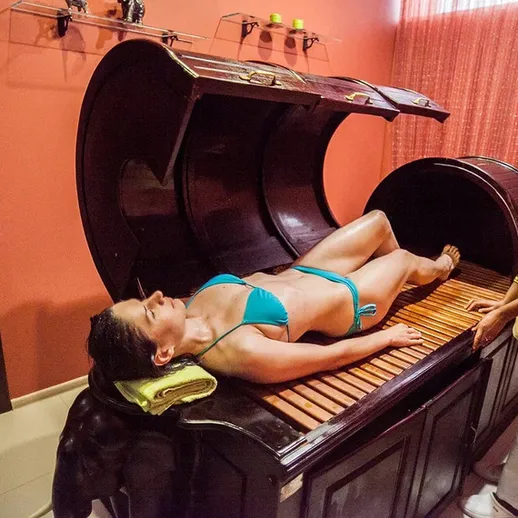 Процедура в спа-салоне, где женщина в купальнике расслабляется под массажем в уютной обстановке