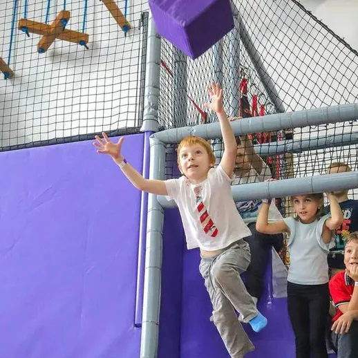 Дети играют в спортивном зале, ловя кубик во время активных игровых занятий