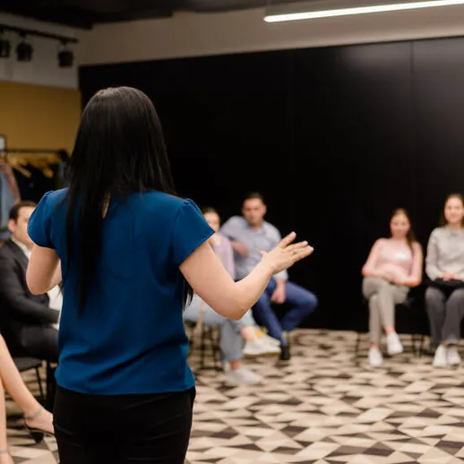 Женщина проводит тренинг по коммуникации для группы людей в современном офисе