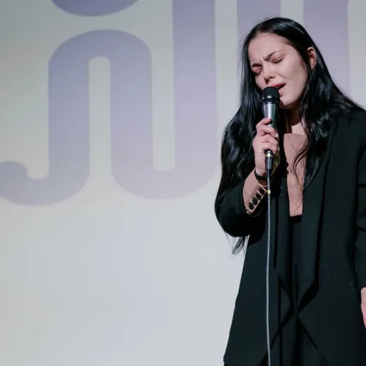 Женщина исполняет трек на сцене культурного мероприятия в Москве, создавая проникновенную атмосферу