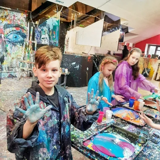 Дети занимаются живописью в арт-студии, используя яркие краски и творческий подход в свободное время