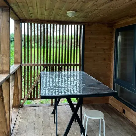 Уютная терраса с деревянным настилом и столом на фоне зелени