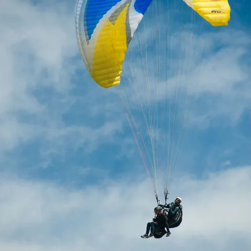 Парапланеры парят в ясном небе над живописным ландшафтом в ясный день