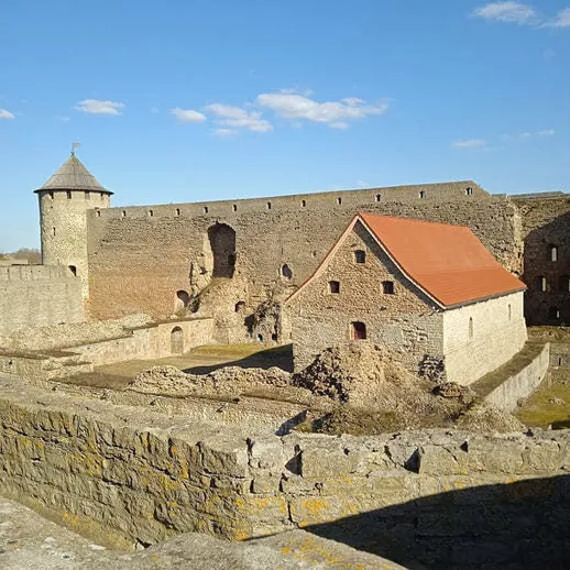 Средневековая крепость с красной крышей и башней в ясный день на фоне голубого неба