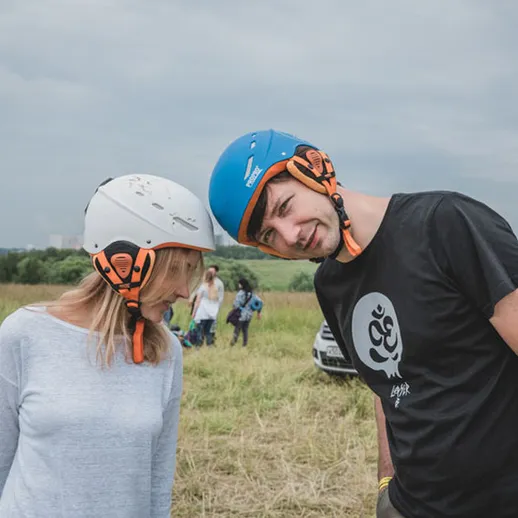 Молодая пара в шлемах на тренировке по парашютному спорту на открытом поле в пасмурный день