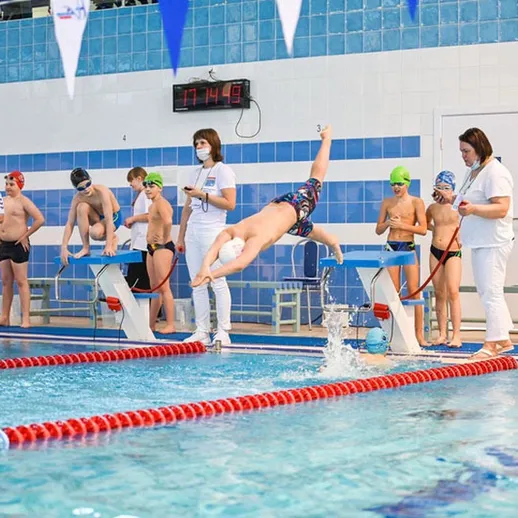 Время соревнований по плаванию для подростков в бассейне с участниками и тренерами