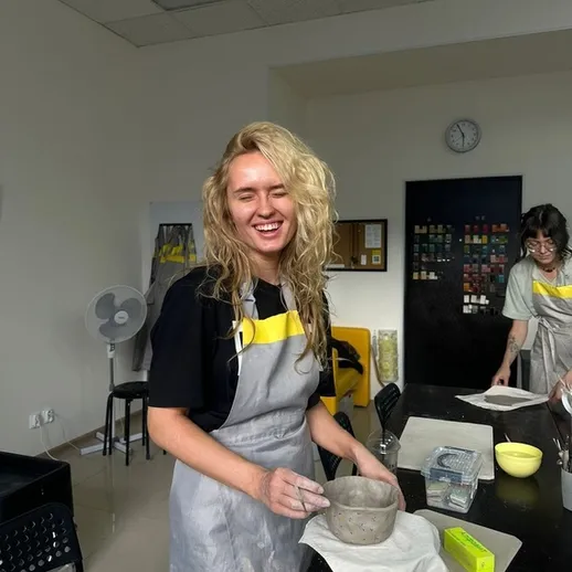 Женщина создает керамический контейнер в мастерской в солнечный день с друзьями в творческой атмосфере