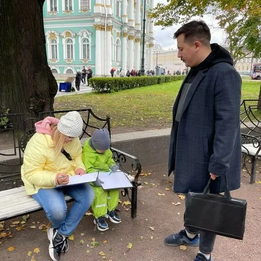 В Петербурге мать с ребенком изучают что-то на скамейке в парке, осень, прохладная погода