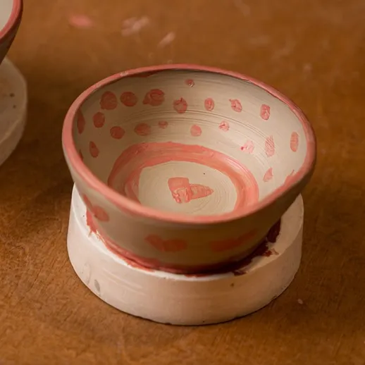 Небольшая глиняная миска с узором на деревянном столе в мастерской керамики