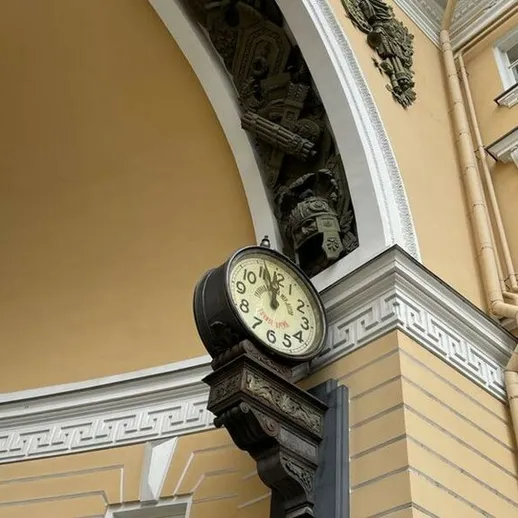 Часы на здании с архитектурными деталями в центре города, отражающие историческую атмосферу