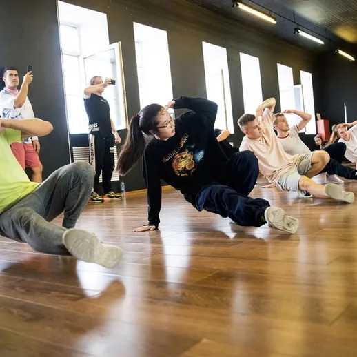 Танцевальный класс, во время которого студенты выполняют тренировку по хип-хопу в студии в светлом помещении