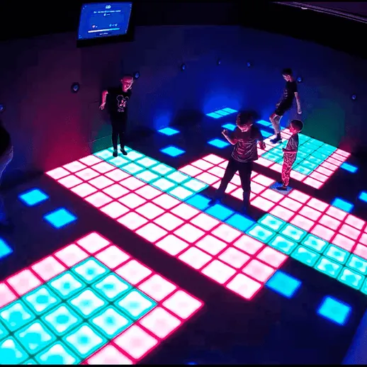 Дети играют на интерактивном световом полу в игровом центре в вечернее время