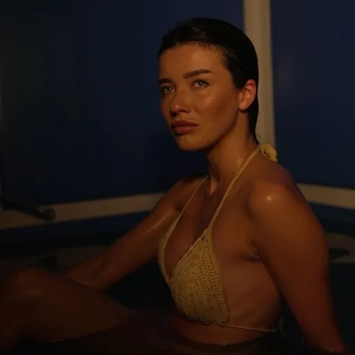 Женщина в купальнике расслабляется в вечернем освещении горячей ванной в уединённом помещении