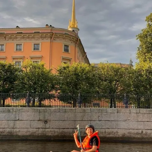 Человек на сапборде в центре города, наслаждающийся спокойной водой у исторического здания в солнечный день