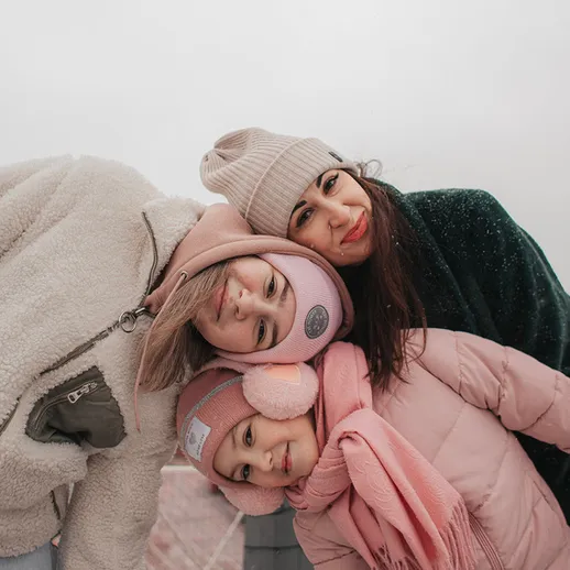 Три девочки наслаждаются холодным днем на улице, позируя на фоне облачного неба к зиме в Москве