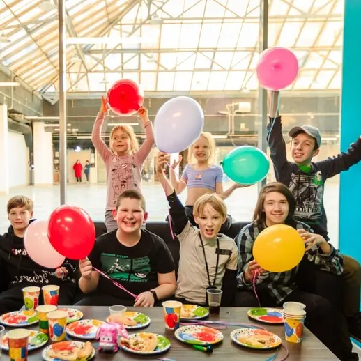 Дети отмечают день рождения в уютном помещении с воздушными шарами и угощениями