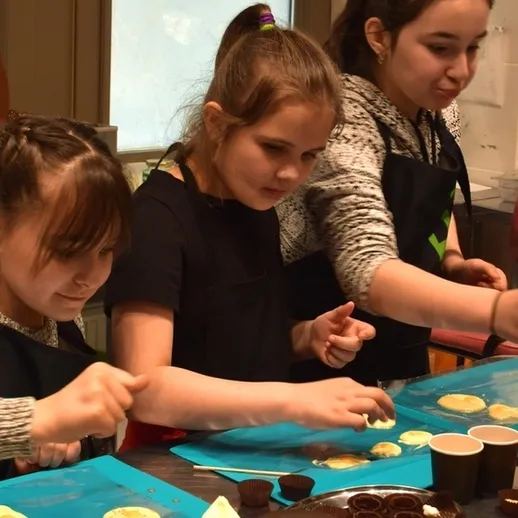 Три девочки готовят десерты на кулинарном мастер-классе в Москве, вовлеченные в создание сладких угощений
