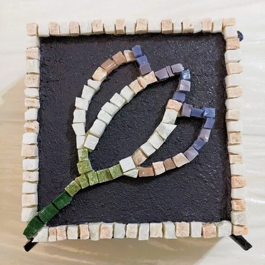 Мозаичная картина цветка на черном фоне, сделанная вручную из разноцветной плитки