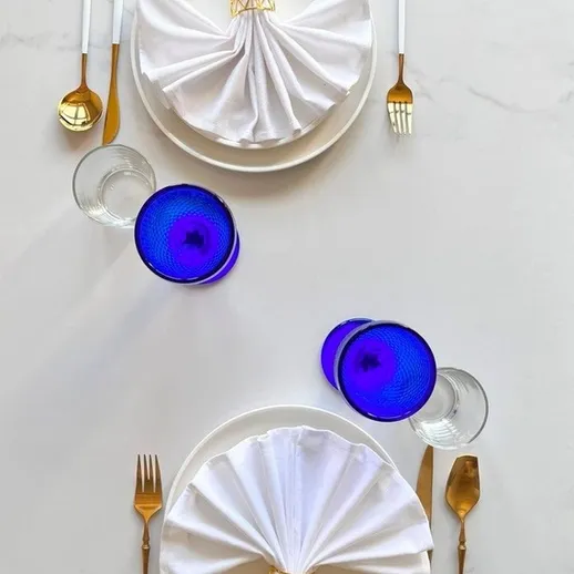 Элегантная сервировка стола с голубыми стаканами и белыми салфетками на столе