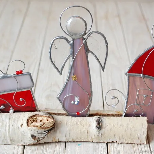 Стеклянные фигурки ангела и домика на природном фоне в зимний уютный вечер