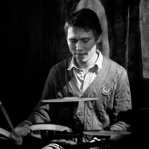 Молодой музыкант играет на ударной установке в уютном клубе на вечеринке