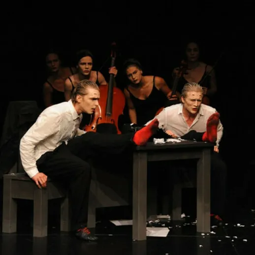 Выразительное театральное выступление группы артистов на сцене в темноте, с ярким светом и напряжённой атмосферой