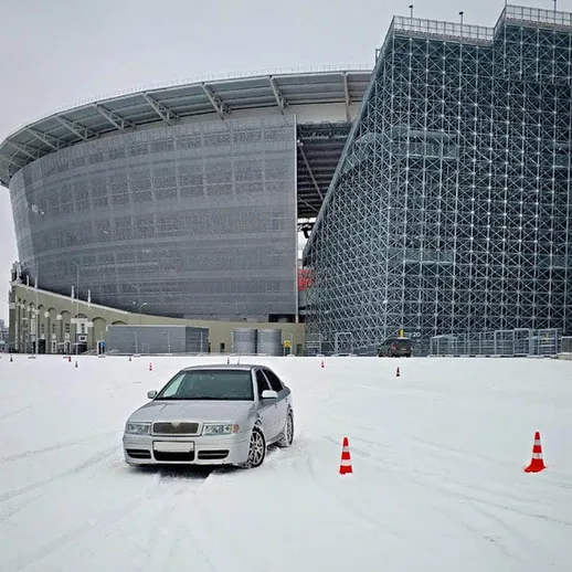 Зимний автогон на снежной площадке около стадиона в метельный день